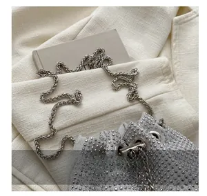 Detail of rhinestone bucket bag featuring silver metallic chain and sparkling crystals