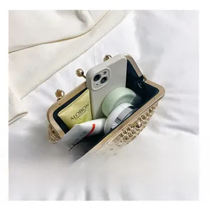 Detail view of woven straw clutch bag interior storage showing phone and cosmetics