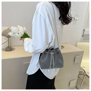 Detail of silver rhinestone bucket bag with pearl drawstring and metal chain strap