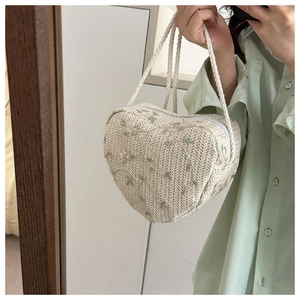 Detailed view of heart-shaped woven bag with delicate floral embroidery and rope handles