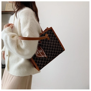 Large retro monogram tote bag with brown leather handles and a silk scarf on shoulder