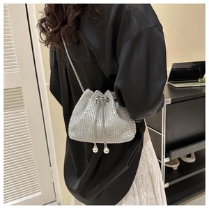 Close-up of silver rhinestone bucket bag with drawstring pearls and chain strap