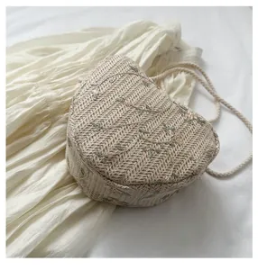 Detailed view of woven straw bag bottom with elegant floral embroidery and rope strap