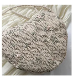 Detailed view of beige heart-shaped woven bag with pink flower embroidery and lace details