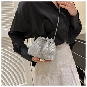 Detailed view of silver rhinestone bucket bag with pearl drawstring and metal chain