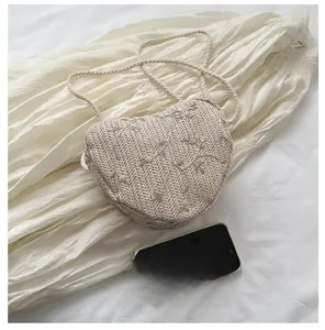 Detail of heart-shaped woven straw mini bag with delicate floral embroidery and strap