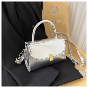 Detail of silver metallic shoulder bag with gold clasp on black blazer background