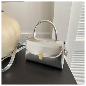 Detail of silver metallic mini bag with gold buckle and smooth leather texture