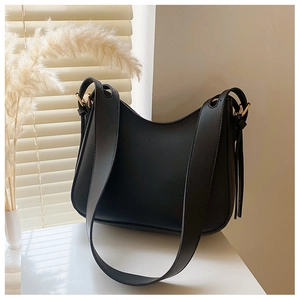 Detail of minimalist black hobo bag with smooth leather texture and gold metal hardware