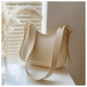 Detail of creamy white hobo bag with smooth texture and golden metal hardware buckles