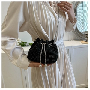 Detail of black rhinestone bucket bag with silver chain and elegant pearl drawstrings