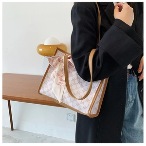 Detail of off-white monogram canvas tote bag with brown leather trim and silk scarf accent