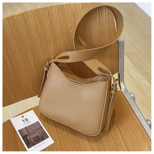 Détail d'un sac à épaule en cuir marron avec fermeture éclair sur une chaise