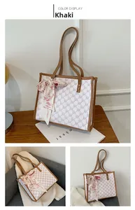 Detail of khaki tote bag with NK logo print and decorative silk scarf accessory
