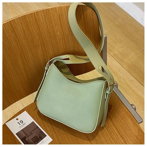 Détail du sac hobo vert menthe avec bandoulière large sur un tabouret en bois naturel