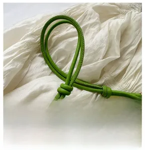 Macro detail of grass green leather handbag handle with sleek stitching and knot design