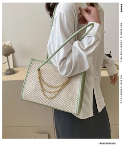 Detail of sage green trim and gold chain layers on a large straw woven tote bag