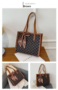 Detail view of large brown tote bag with NK pattern and silk scarf on wooden table