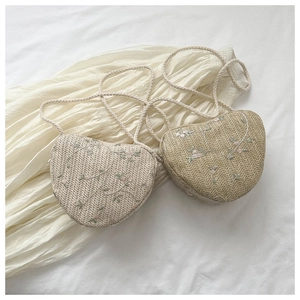 Close-up of woven heart bags with delicate floral embroidery and braided rope straps