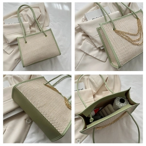Detail view of large woven tote bag with green leather trim and golden chains