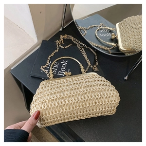Detailed close-up of a handwoven straw clutch with gold clasp and chain shoulder strap