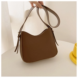 Gros plan d'un sac à bandoulière demi-lune marron avec détails dorés et boucle latérale