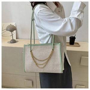 Detail view of woven shoulder bag featuring green leather trim and golden chain accents