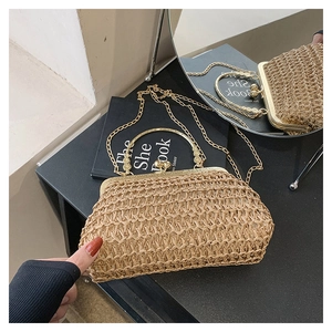 Detail of hand-woven straw bag featuring golden metal frame and round bead clasp