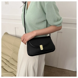 Detail of a black matte leather saddle bag with a golden square clasp and long strap