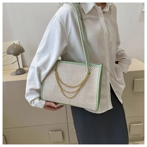 Detail of woven tote bag featuring light green leather trim and golden chain accents