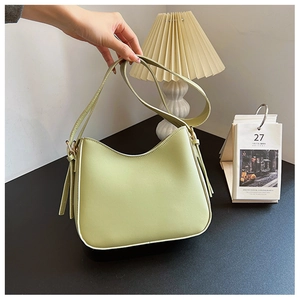 Détail du sac à bandoulière demi-lune vert clair en similicuir lisse dans un décor chaleureux