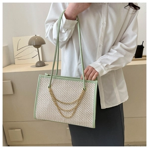 Detail of woven tote bag featuring light green leather trim and golden chain accents