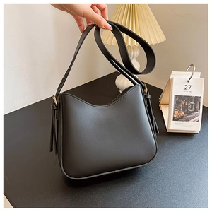 Détail du sac à bandoulière croissant en cuir noir avec pompon et longue lanière