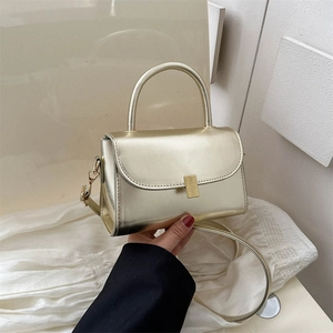 Champagne gold metallic top handle crossbody bag with gold buckle and leather strap