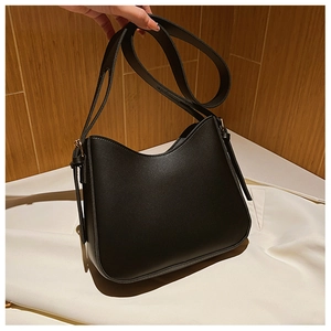 Détail d'un sac hobo minimaliste en similicuir noir avec bandoulière large et courbe