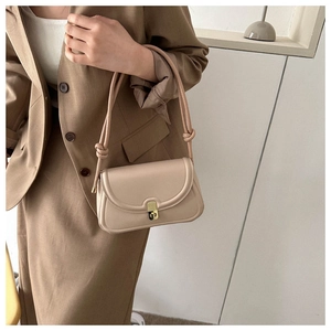 Detail of minimalist saddle bag with gold buckle and knotted strap on female model