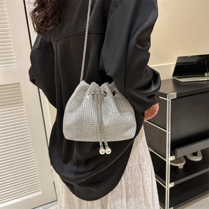 Chic silver rhinestone bucket bag with pearl drawstring and metal chain strap on model