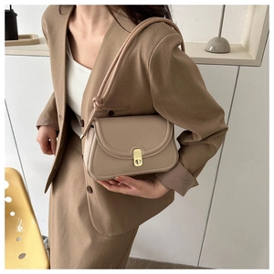 Detail of minimalist taupe saddle bag with gold metal clasp and knot strap detail