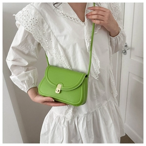Bright green saddle bag with gold metal buckle shown on model in white lace dress