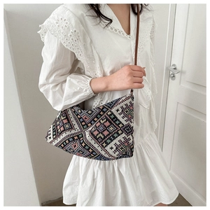 Detailed close-up of bohemian woven crossbody bag with colorful geometric patterns