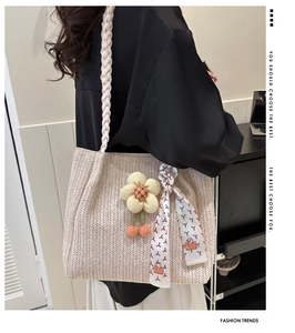 Détail du sac cabas en paille avec anses torsadées, charms marguerites et foulard en soie
