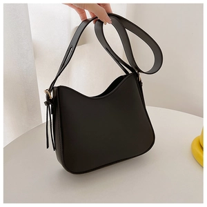 Détail d'un sac bandoulière en cuir noir mat aux lignes épurées et large sangle