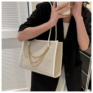 Detail of large woven tote with gold chain tassels and white leather trim accents