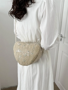 Handwoven heart-shaped straw crossbody bag featuring delicate floral embroidery detail