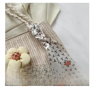 Détail d'un sac en paille avec fleur en tissu et foulard en soie à motifs élégants