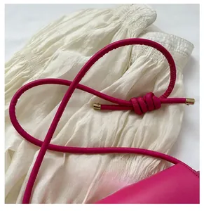 Detail of rose pink leather shoulder bag featuring a slim strap with gold metal tips