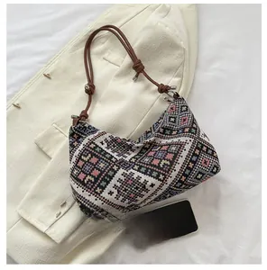 Detailed close-up of woven geometric pattern handbag with a smartphone for size scale