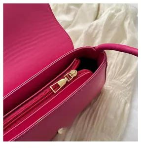 Detailed macro view of magenta shoulder bag showing gold metal zipper and neat lining