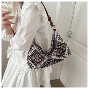 Close-up of ethnic woven shoulder bag with colorful geometric patterns and brown leather strap