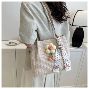 Détail d'un sac cabas tissé avec texture à chevrons et pendentif floral élégant